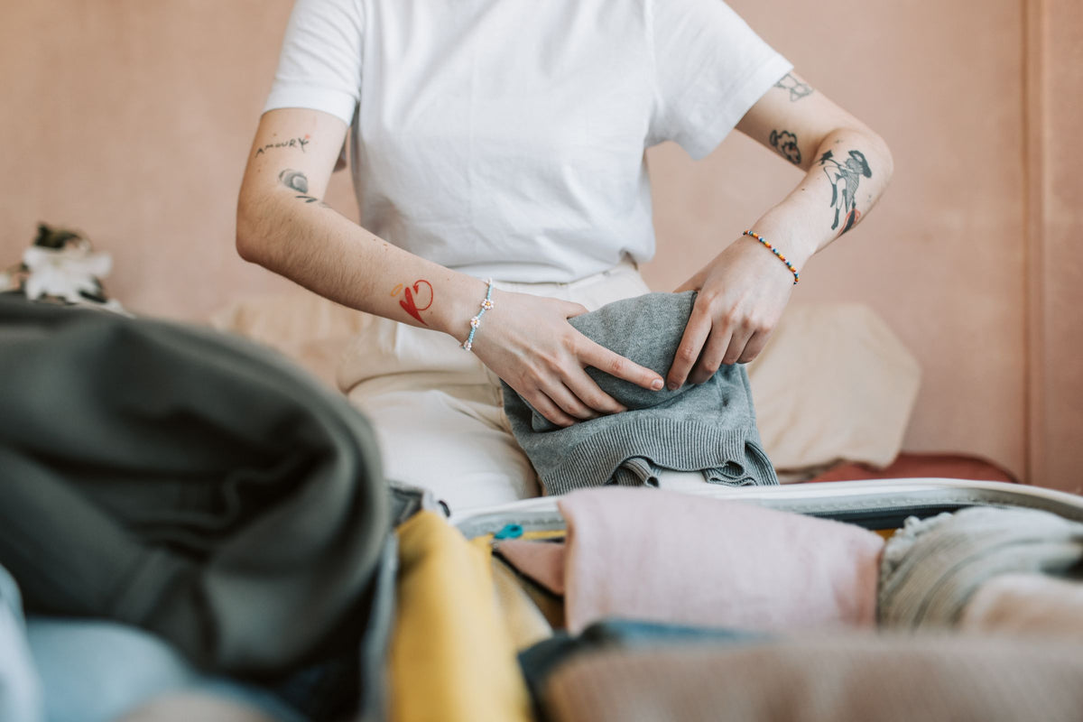 Hombre preparando la maleta con camisas dobladas